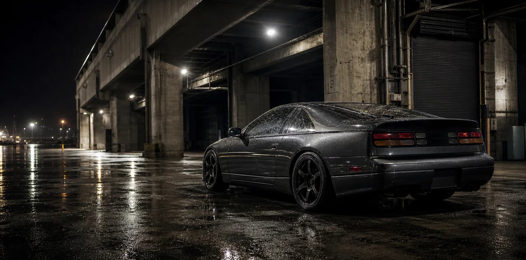 Graphite coupe beneath industrial lights at night